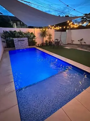 a blue swimming pool in a backyard at night at Sönmez Private Villa in Cavite