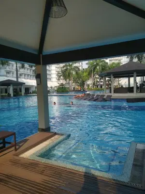 a swimming pool at a resort with people in it at Shell Family Suites Ocean & MOA view in Manila