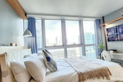 a bedroom with a white bed and a large window at LuxeStaysMnl Coastal Chic Netflx 380MBPS Pool BGC in Manila