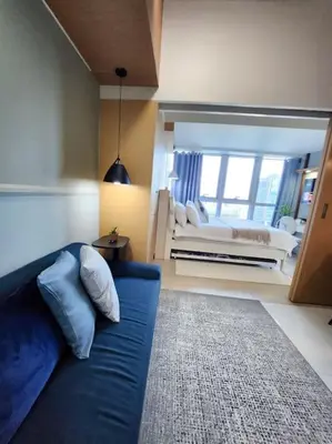 a living room with a blue couch and a bed at LuxeStaysMnl Coastal Chic Netflx 380MBPS Pool BGC in Manila