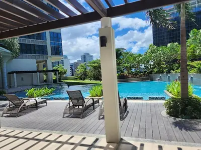 a patio with chairs and a swimming pool at LuxeStaysMnl Coastal Chic Netflx 380MBPS Pool BGC in Manila