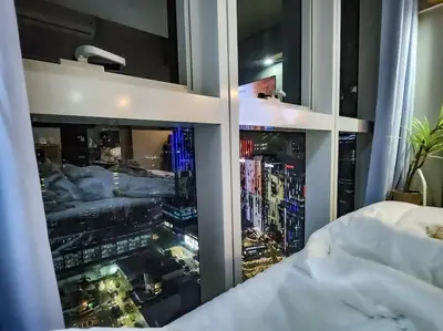 a bedroom with a view of a city seen through a window at LuxeStaysMnl Coastal Chic Netflx 380MBPS Pool BGC in Manila
