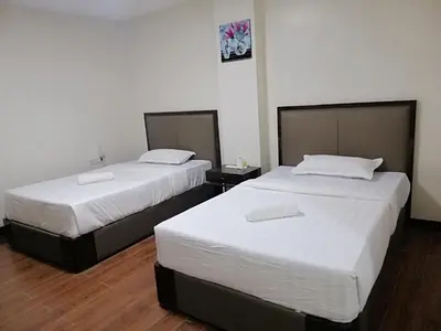 two beds in a hotel room with white sheets at Meaco Royal Hotel - Biñan Laguna in Biñan