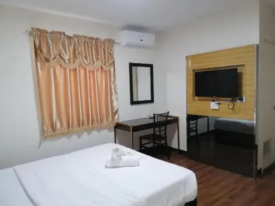 a bedroom with a bed and a desk and a television at Meaco Royal Hotel - Biñan Laguna in Biñan