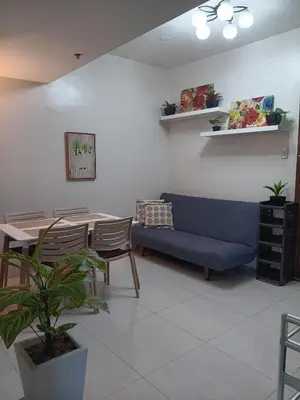 a living room with a blue couch and a table at CB Homestay 2BR Unit Taguig Self-Check-In & Wi-Fi in Manila