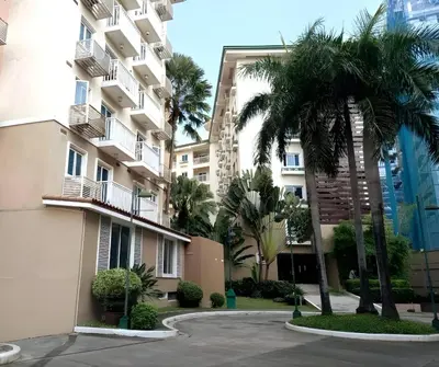 a building with palm trees in front of it at CB Homestay 2BR Unit Taguig Self-Check-In & Wi-Fi in Manila