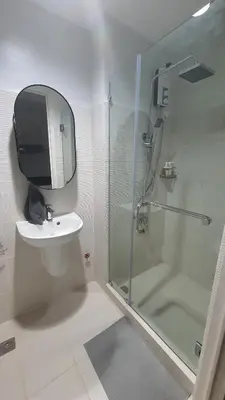 a bathroom with a shower and a sink and a mirror at The New Villa at Sea Residences in Manila