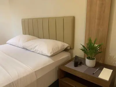 a bed with a pillow and a table with a potted plant at Shell Residences Mall of Asia Pasay in Manila