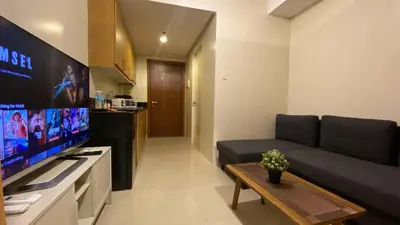 a living room with a couch and a flat screen tv at Shell Residences Mall of Asia Pasay in Manila