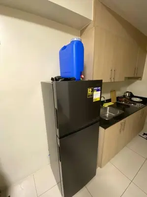a kitchen with a refrigerator with a blue container on top at Breeze Residences 26th floor in Manila