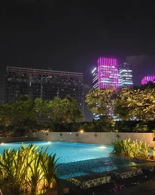 a swimming pool at night with buildings in the background at Uptown Parksuites Tower 1 at BGC - Staycations Up Above 12 in Manila