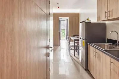 a kitchen with wooden cabinets and a stainless steel refrigerator at BTS Be The Ace at MOA in Manila