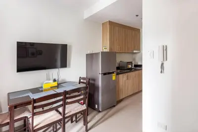 a kitchen with a table and a stainless steel refrigerator at BTS Be The Ace at MOA in Manila