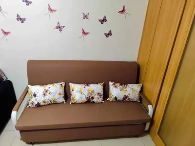 a couch with three pillows and butterflies on the wall at Shell Residences MOA 3 in Manila