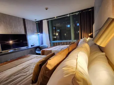 a hotel room with two beds and a flat screen tv at LUXESTAYSMNL ELEGANT FAMILY 2BR SUITE POOLGYM 400MBPS WIFI NETFLX AMAZING CITY VIEW in Manila
