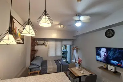 a living room with a bed and a couch and a tv at Affordable Condo in Makati w/ Wi-Fi, Netflix, Pool in Manila