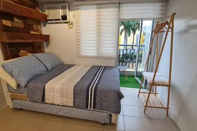 a bedroom with a bed and a chair and a window at Affordable Condo in Makati w/ Wi-Fi, Netflix, Pool in Manila