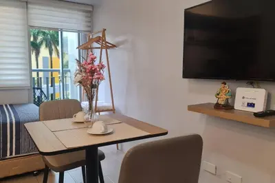 a dining room table with a vase of flowers on it at Affordable Condo in Makati w/ Wi-Fi, Netflix, Pool in Manila