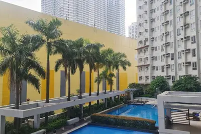 a pool with palm trees in front of a building at Affordable Condo in Makati w/ Wi-Fi, Netflix, Pool in Manila
