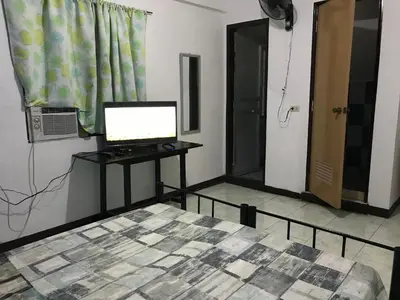 a bedroom with a bed and a computer on a desk at Aladino Hostel in Dasmariñas