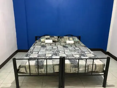 a bed in a room with a blue wall at Aladino Hostel in Dasmariñas