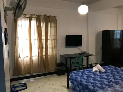 a bedroom with a bed and a desk and a television at Aladino Hostel in Dasmariñas