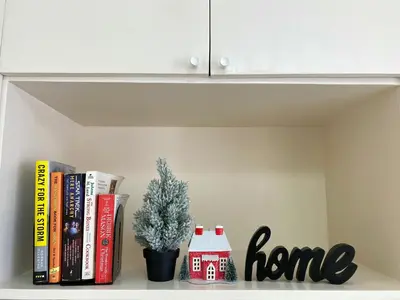a shelf with books and a house ornament and a christmas tree at Avida Towers New Manila near Crame, Cubao and Greenhills in Manila