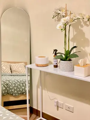 a table with flowers on it with a mirror at Cozy 1 BR Scandinavian/Tropical Condo with Balcony & Parking in Manila