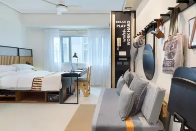 a bedroom with a bed and a desk at Relaxing Apt Bgc Business Ready with 84inch Cinema in Manila