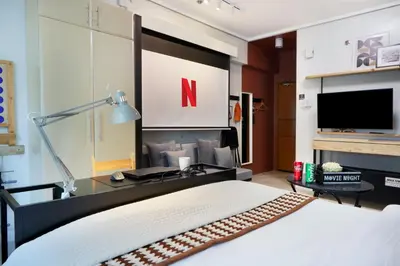 a bedroom with a bed with a desk and a tv at Relaxing Apt Bgc Business Ready with 84inch Cinema in Manila