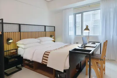 a bedroom with a bed and a desk with a laptop at Relaxing Apt Bgc Business Ready with 84inch Cinema in Manila