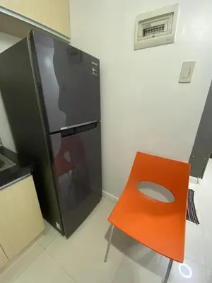 a black refrigerator and an orange chair in a kitchen at 60 percent Off Deluxe Ocean View Rooms FREE Pool and FREE Sauna Access Included Perfect Location Near US Embassy, NAIA, Makati, BGC, Mall of Asia, and Chinatown Dont Miss Out Book Now and Save Updated Price 2025 in Manila