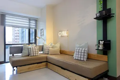 a living room with a couch with pillows on it at Spacious Family Sleeper BGC & 84inch Cinema in Manila