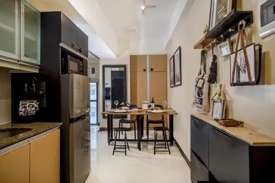 a kitchen with a table with chairs and a refrigerator at Max Dwell Bgc Creative Space with 84 