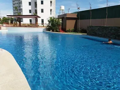 a large blue swimming pool with a person laying in it at Staycation bigger room in Manila
