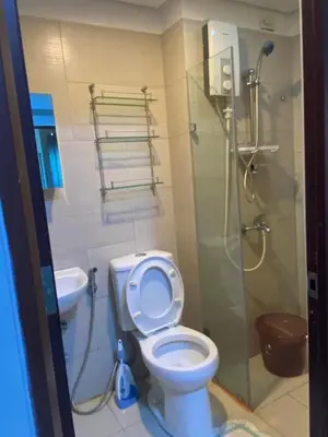 a bathroom with a toilet and a glass shower at Staycation bigger room in Manila