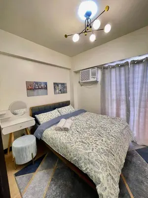 a bedroom with two beds and a table and a ceiling fan at Brand new condo for travelers in Paranaque near airport in Manila