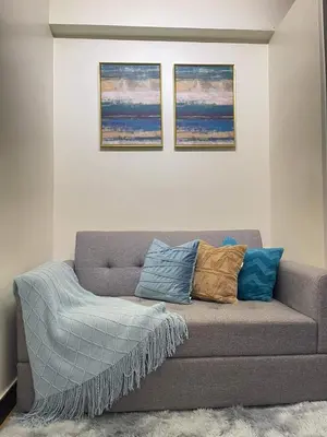 a couch in a living room with three pictures on the wall at Brand new condo for travelers in Paranaque near airport in Manila