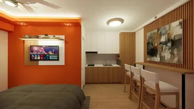 a bedroom with an orange wall with a bed and a kitchen at Near Manila Airport, MAILZ HOMEZ COZY Hotel Style Studio Condo, Avida Towers Sucat, Full Kitchen, Swimming Pool, WIFI, 5G in Manila