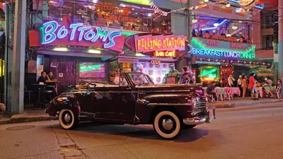 an old black car parked on a city street at night at Near Manila Airport, MAILZ HOMEZ COZY Hotel Style Studio Condo, Avida Towers Sucat, Full Kitchen, Swimming Pool, WIFI, 5G in Manila
