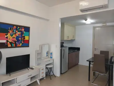 a living room with a television and a kitchen at Alps at 150 Newport Blvd Condominum near T3 in Manila