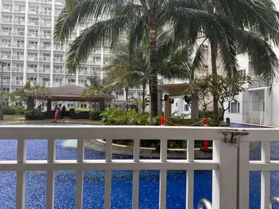 a white fence with palm trees in front of a building at Direct Pool Access Shore Residences MOA Pasay Near Airport in Manila