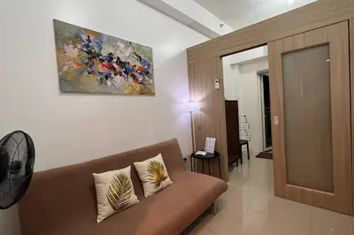 a living room with a couch and a painting on the wall at Direct Pool Access Shore Residences MOA Pasay Near Airport in Manila