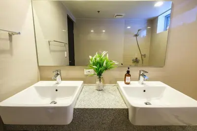 two white sinks in a bathroom with a mirror at Spacious 2BR Apartment in BGC with Workspace & Washer in Manila