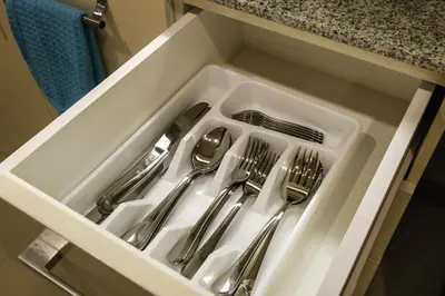 a white sink with silver utensils in a drawer at Spacious 2BR Apartment in BGC with Workspace & Washer in Manila