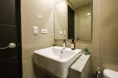 a bathroom with a white sink and a mirror at Spacious 2BR Apartment in BGC with Workspace & Washer in Manila