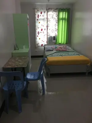 a small bedroom with a bed and a table and chair at AGB Anchorage Inn, studio room in Manila