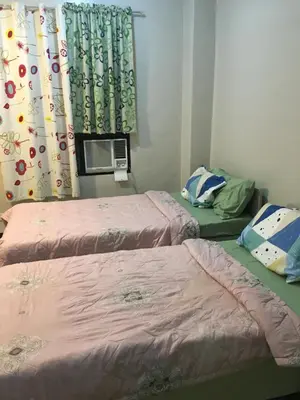 a room with two beds and a window with curtains at AGB Anchorage Inn, studio room - 2 single beds in Manila