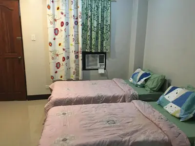 a room with two beds and a window with a curtain at AGB Anchorage Inn, studio room - 2 single beds in Manila