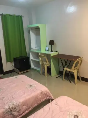 a room with two beds and a desk and a green curtain at AGB Anchorage Inn, studio room - 2 single beds in Manila